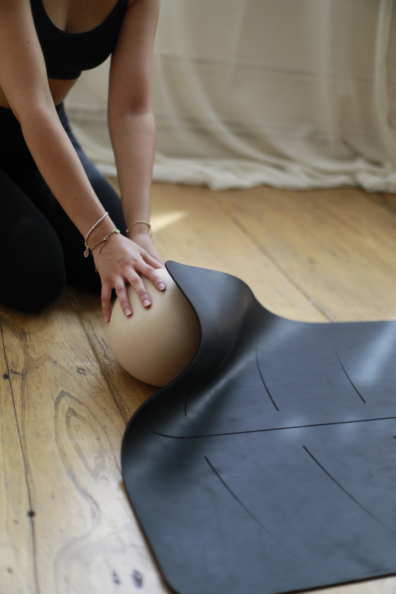 Les mains de Clara accompagnent un ballon de Pilates sur le tapis
